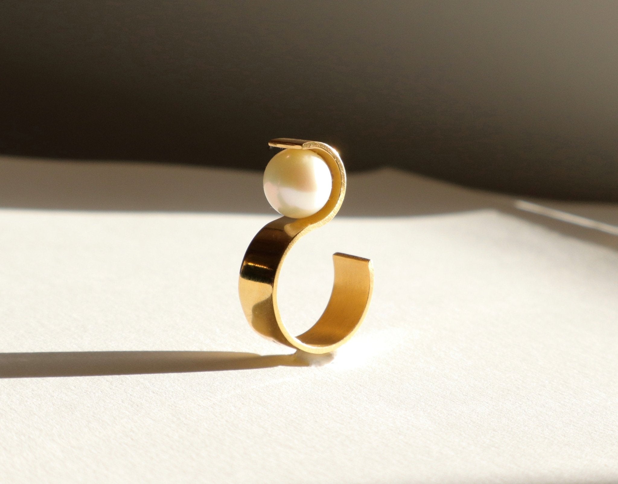 Vue de profil de la bague S montrant sa structure géométrique en vermeil et l'équilibre parfait de sa perle.