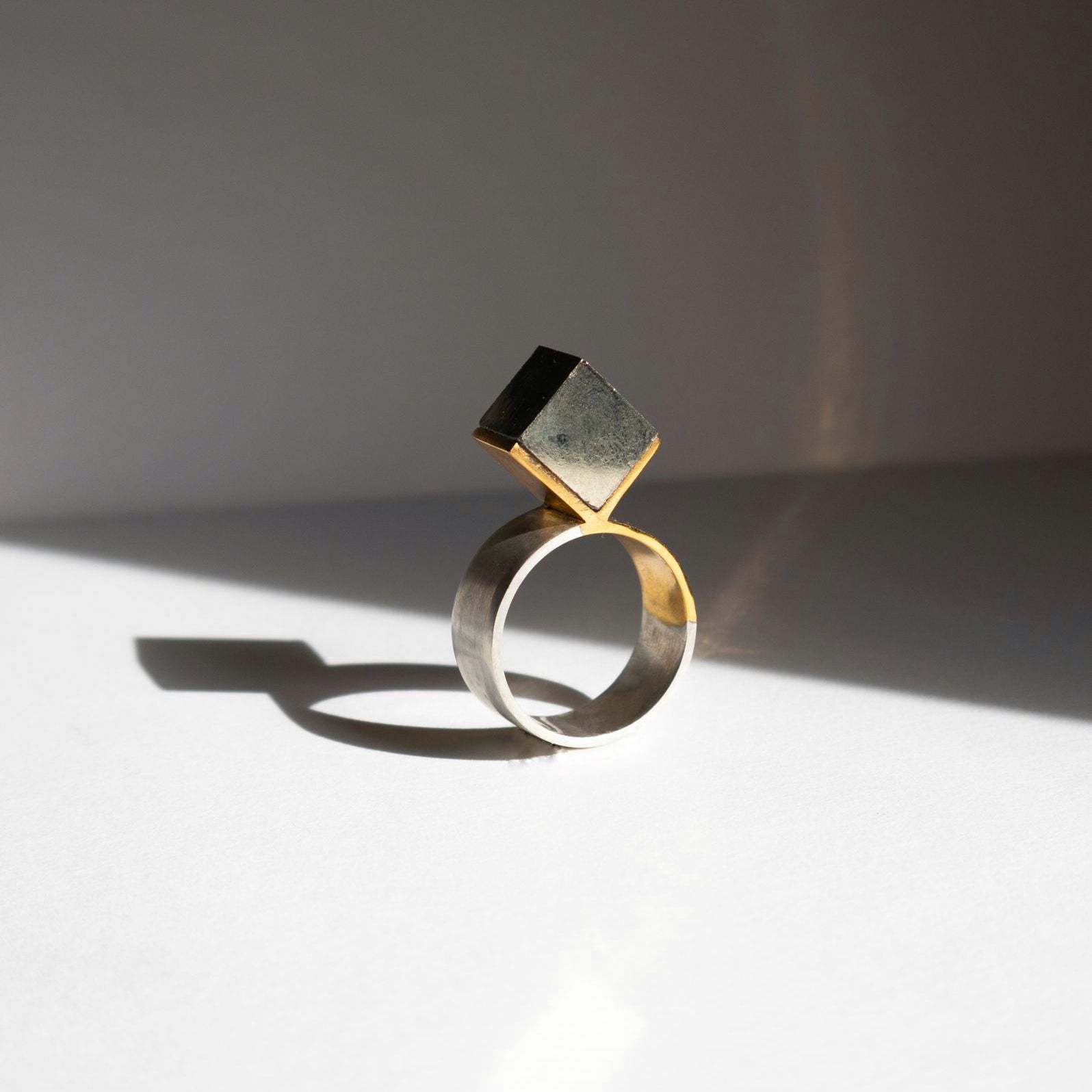 Bague X, anneau argent 950 et serti triangle vermeil avec cube de pyrite naturelle, vue de face fond beige, Atelier Grandval.